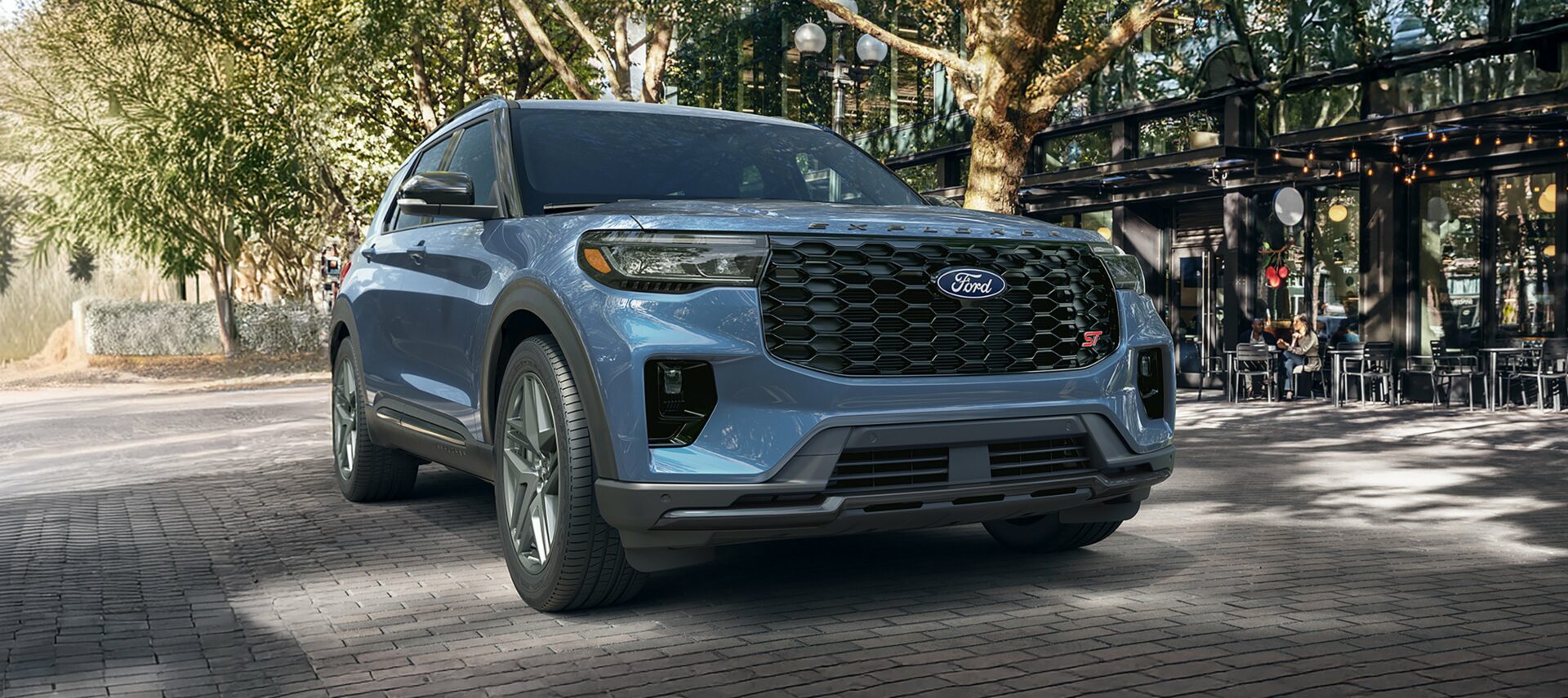 A light blue 2027 Ford Explorer on a brick street under mature trees