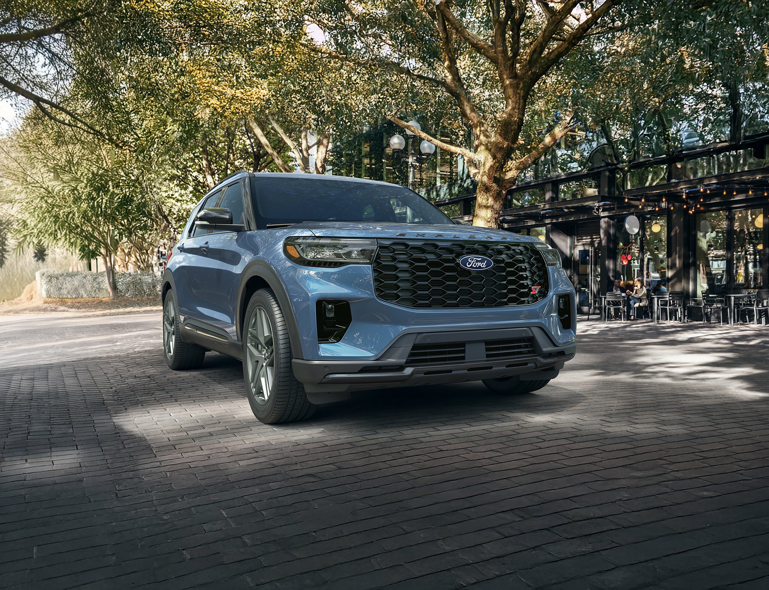 A light blue 2027 Ford Explorer on a brick street under mature trees