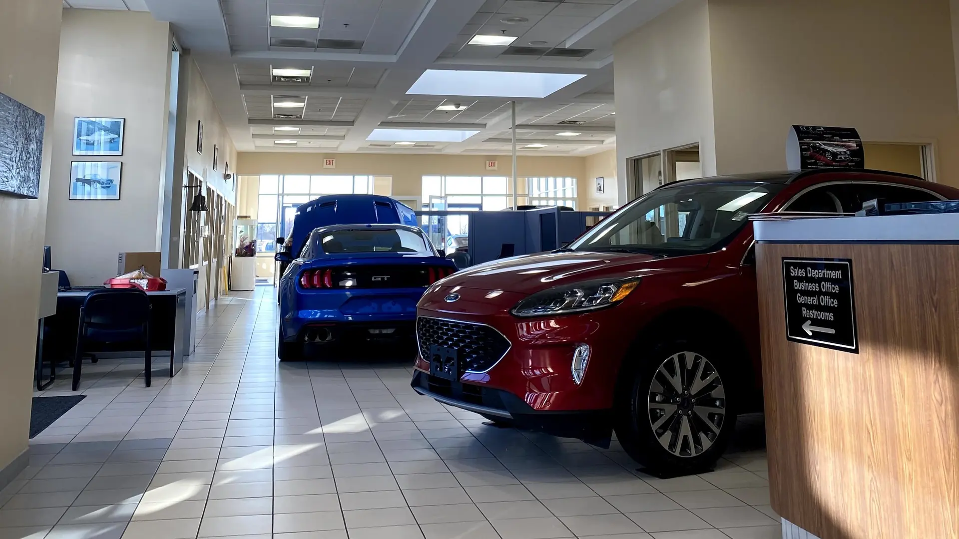 The Huntley Ford showroom floor, with a red Ford Escape and a sign pointing to the sales department and business office