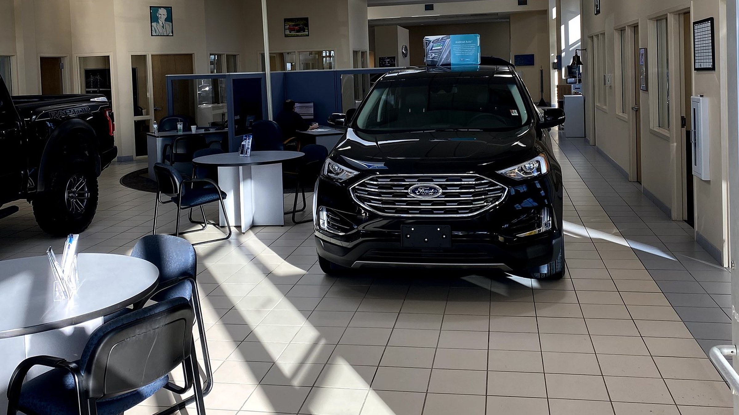 A Ford Edge on the showroom floor at Huntley Ford, with the business office desks behind it.
