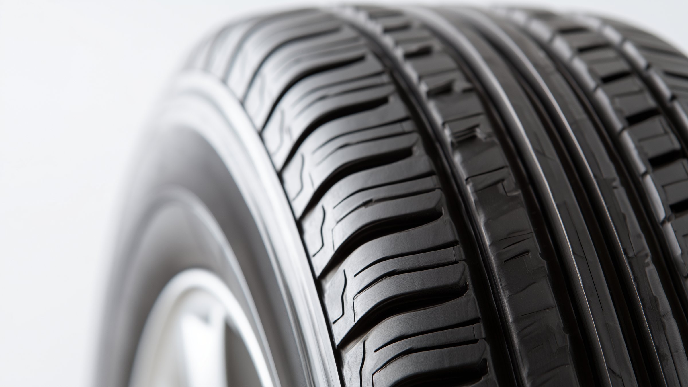 Close-up of the tread of a new all-season tire, its ribs and sipes lit from above