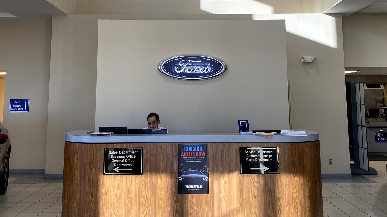 The Huntley Ford front desk under the Ford oval, with signs pointing left to sales and the business office and right to service, the customer lounge, and parts