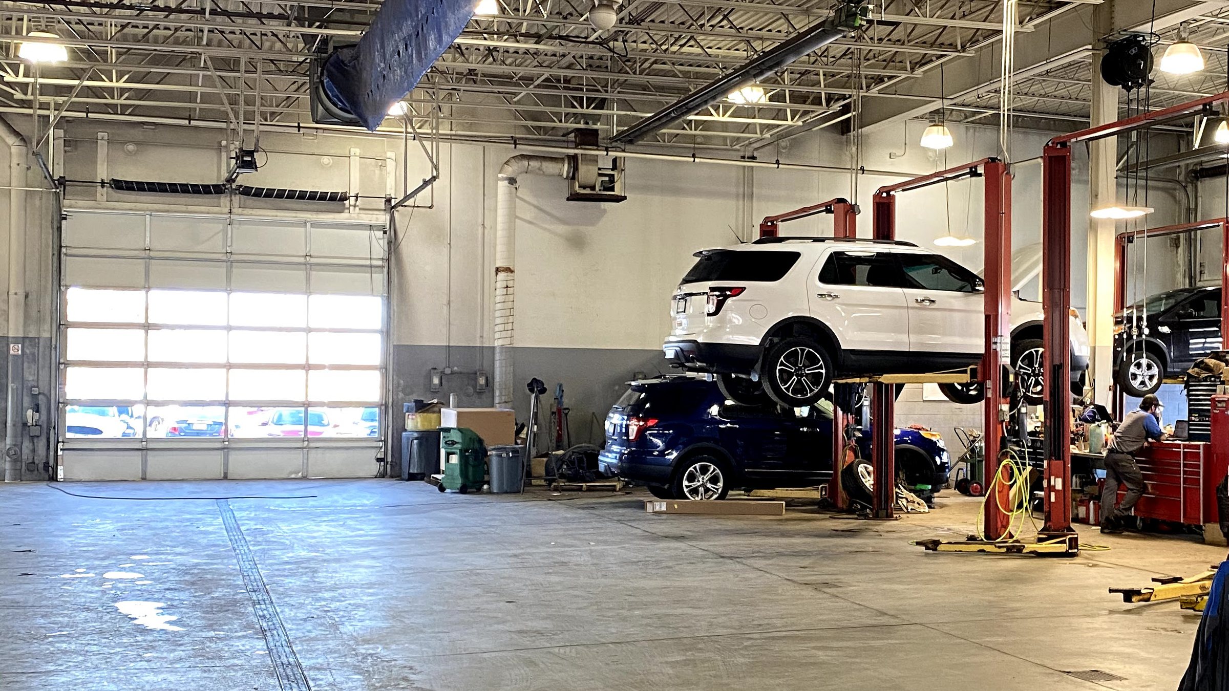 Inside the Huntley Ford service department, with vehicles raised on lifts and a technician at a workbench